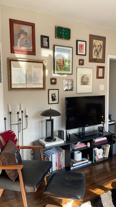 a living room filled with furniture and framed pictures on the wall behind a flat screen tv