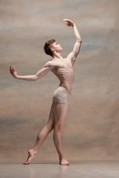 a male ballet dancer posing for the camera with his arms stretched out in front of him