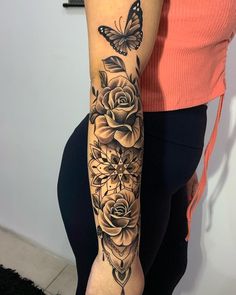 a woman's arm with flowers and a butterfly tattoo on her left arm, which is black and white