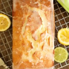 a loaf of bread sitting on top of a cooling rack next to sliced lemons