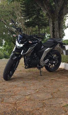 a black motorcycle parked next to a tree