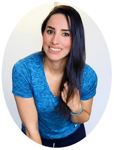 a woman with long dark hair wearing a blue shirt and smiling at the camera in front of a white circle