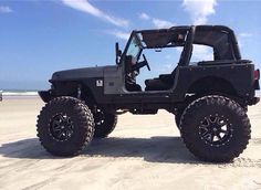 a black jeep parked on top of a sandy beach