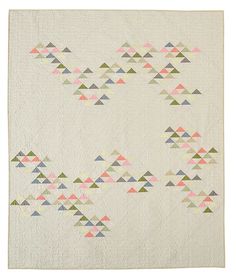 a white quilt with colorful triangles on the front and back, in pastel colors