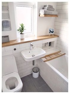 a bathroom with a toilet, sink and bathtub next to a window in it