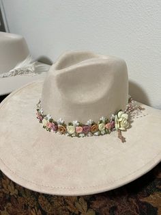 'Bride' is one of our custom hats with a pearl and roses (pink, white and lavender) There is a Bride pin (magnet so it can be moved or removed easily so the hat can be worn after the wedding).   This hat is polyester and cotton blend so it is lightweight with a wider Fedora Brim.  Color is off white.  There is no burning on this hat, however it can be added to customize your hat.  Bride is also apart of our wedding collection.  Our hats are one size fits all.  All hats are custom One-of-a Kind so the hat is special to the wearer.   With hand made products there are no refunds with either pre-made or custom made products. When shipping your product we ensure your product is protected. *Shipping fees are separate. Adjustable Hat With Handmade Flowers As Gift, Adjustable Hats With Handmade Flowers For Gifts, Adjustable Hats With Handmade Flowers As Gift, Adjustable Fedora Mini Hats For Wedding, Spring Wedding Fedora Adjustable Fit, Spring Wedding Fedora Adjustable, Spring Wedding Adjustable Fedora, Pink Fedora Hat For Wedding, Pink Fedora For Wedding