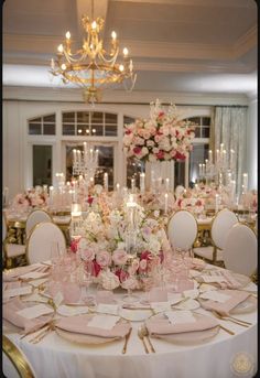 the table is set with pink and white flowers, candles, and napkins on it