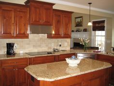 a large kitchen with wooden cabinets and granite counter tops, along with an island in the middle