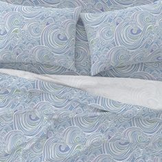 a blue and white comforter set with wavy designs on it's bedding