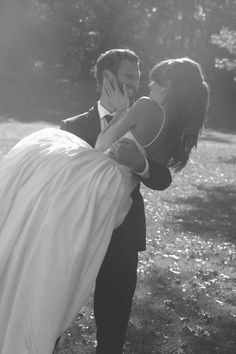 a man in a tuxedo carrying a woman on his back through the grass