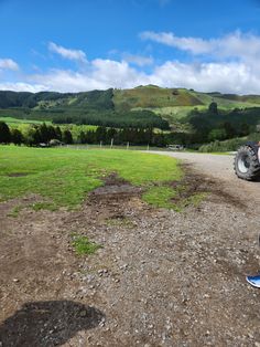 a person standing in front of a truck on a dirt road with mountains in the background