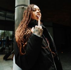 a woman standing next to a pole with her finger in her mouth