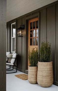 two large planters sitting on the front porch next to a chair and door way