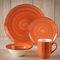 an orange dinnerware set with two cups and one plate on a white countertop