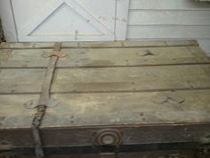 an old trunk is sitting in front of a white door with a brown handle on it