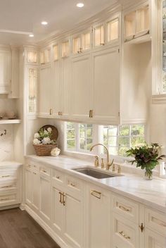 a kitchen with white cabinets and gold handles on the counter tops, along with a sink