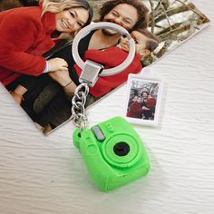 a green camera keychain sitting on top of a table next to a photo