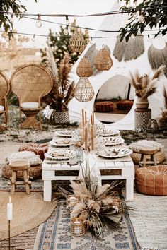 a table set up with plates and place settings in front of a teepee tent