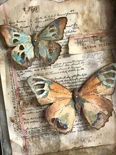 three butterflies are sitting on top of an old piece of paper