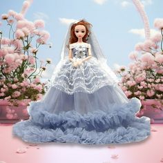 a barbie doll dressed in a blue wedding gown and veil with pink flowers behind her