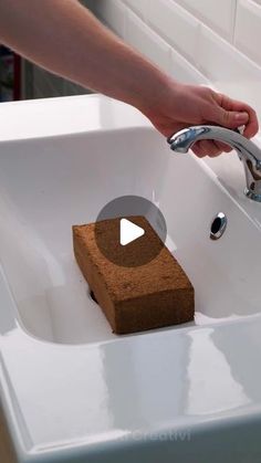 a person is washing their hands in a white bathroom sink with soap on the edge