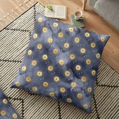 a blue floor pillow with gold polka dots on it and a cup of coffee next to it