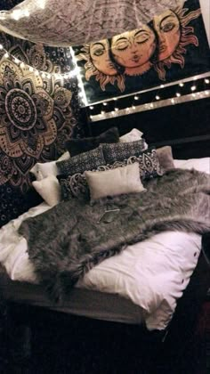 a bed with blankets, pillows and lights on the headboard in a room that is decorated with wall hangings