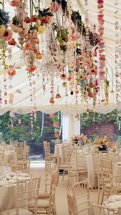 the inside of a marquee decorated with flowers and chandeliers hanging from the ceiling