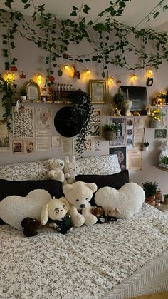 there are stuffed animals on the bed in this room with plants and pictures above it