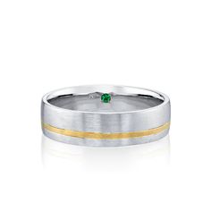 a wedding band with two gold stripes and a green stone in the center on a white background