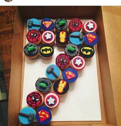 a box filled with cupcakes covered in icing and decorated like superheros