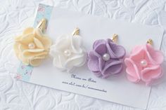 three flower clips with pearls on them sitting on a piece of paper next to a card