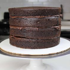 a chocolate cake sitting on top of a white platter next to a black stove