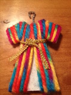 an ornament made to look like a baby's rainbow sweater with gold chains