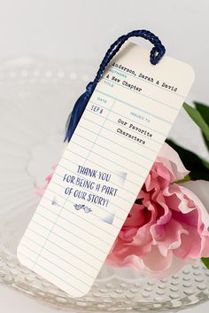 there is a paper tag with writing on it next to pink flowers and greenery