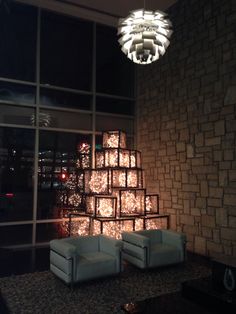 two white chairs sitting in front of a wall with lights on it and a chandelier hanging from the ceiling