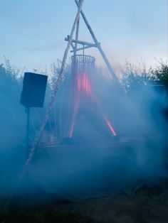 an old wooden structure in the middle of some misty grass with a red light on it