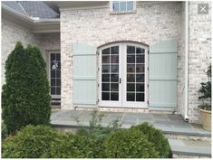 a brick house with blue shutters and stone steps leading to the front door area