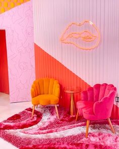 two chairs and a table in front of a wall with pink, orange, and yellow colors