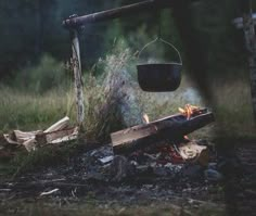 a fire pit sitting in the middle of a forest next to a pile of logs