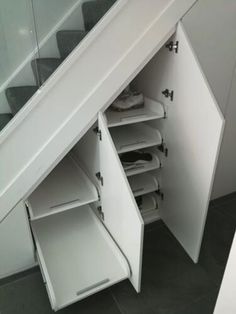 an open closet under the stairs with shoes and other items in it's storage compartment