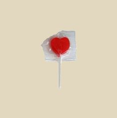 a red heart lollipop sitting on top of a piece of white tissue paper