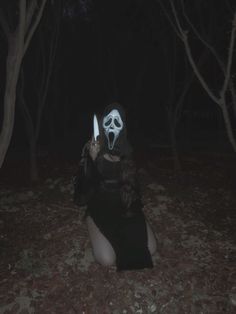 a woman wearing a mask and holding a knife in the dark with her mouth open