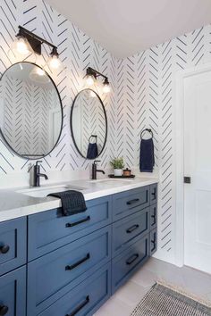 a bathroom with blue cabinets and two round mirrors