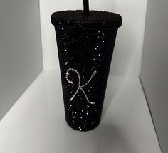 a black cup with a pink ribbon on it and a straw in the middle is sitting on a white surface