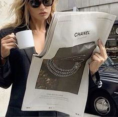 a woman holding a coffee cup and reading a chanel newspaper