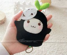 a hand holding a small black and white animal with a green leaf on it's head