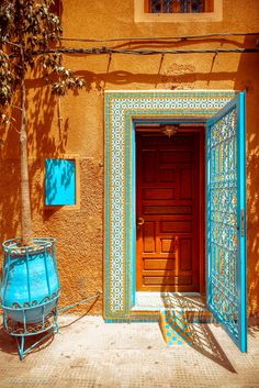 an orange building with a blue door and window sill next to a planter