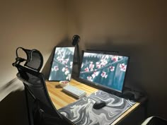 two computer monitors sitting on top of a wooden desk