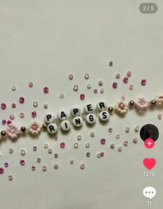 the word paper rings spelled out with beads and pearls on a white surface next to hearts